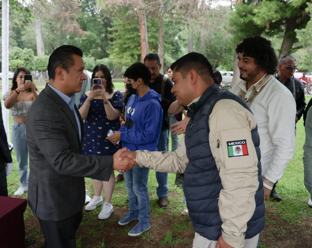 Lic. Carlos torres Piña, Secretario de gobierno saluda a elemento de seguridad durante la entrega de armamento a la comunidad de San Francisco Peribán
